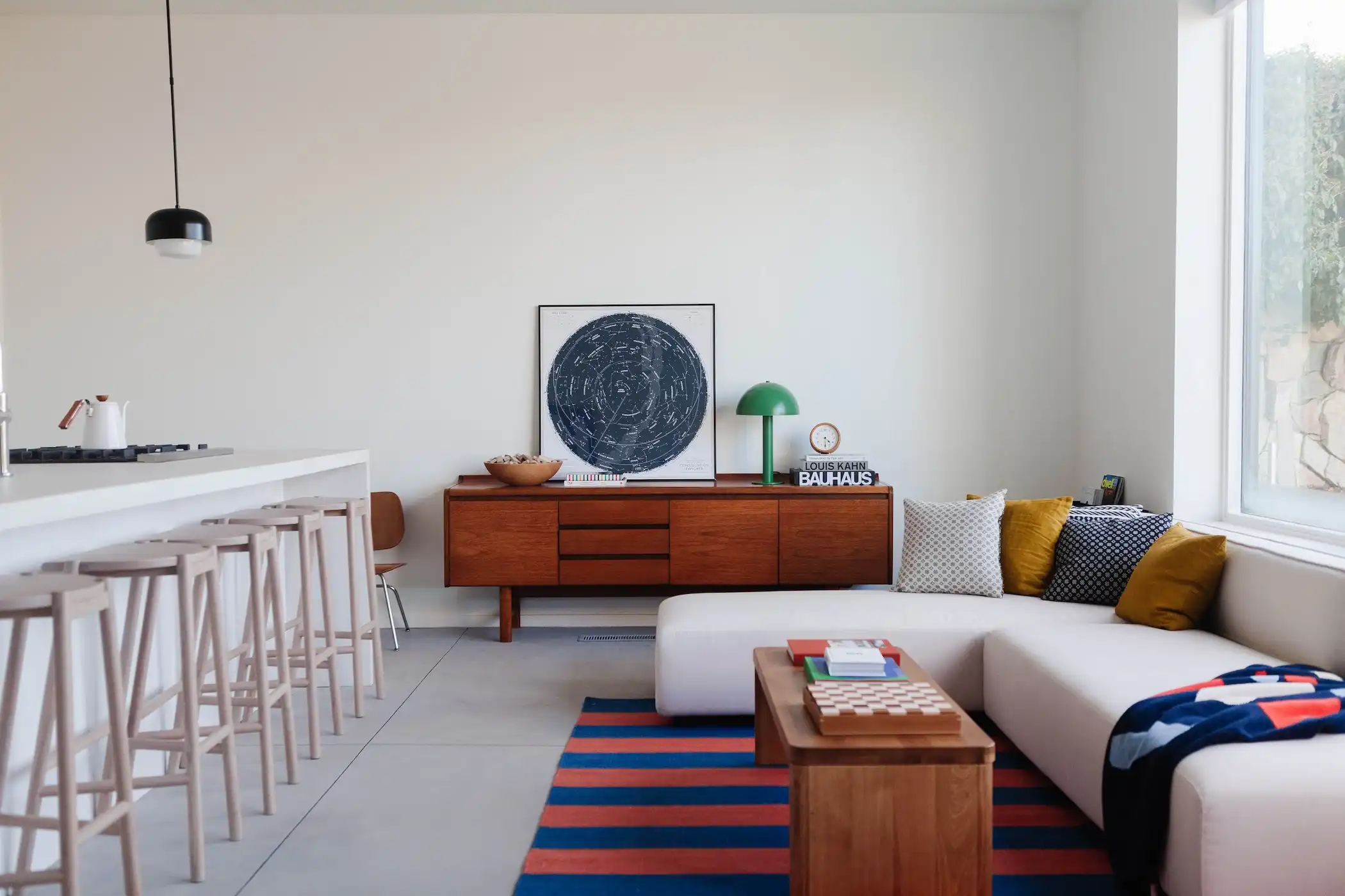 Living room with a bed and a table. It features a combination of furniture and interior design elements like a bed, table, cabinetry, and a vase. The room is designed with a minimalist aesthetic and seems well-organized and spacious.