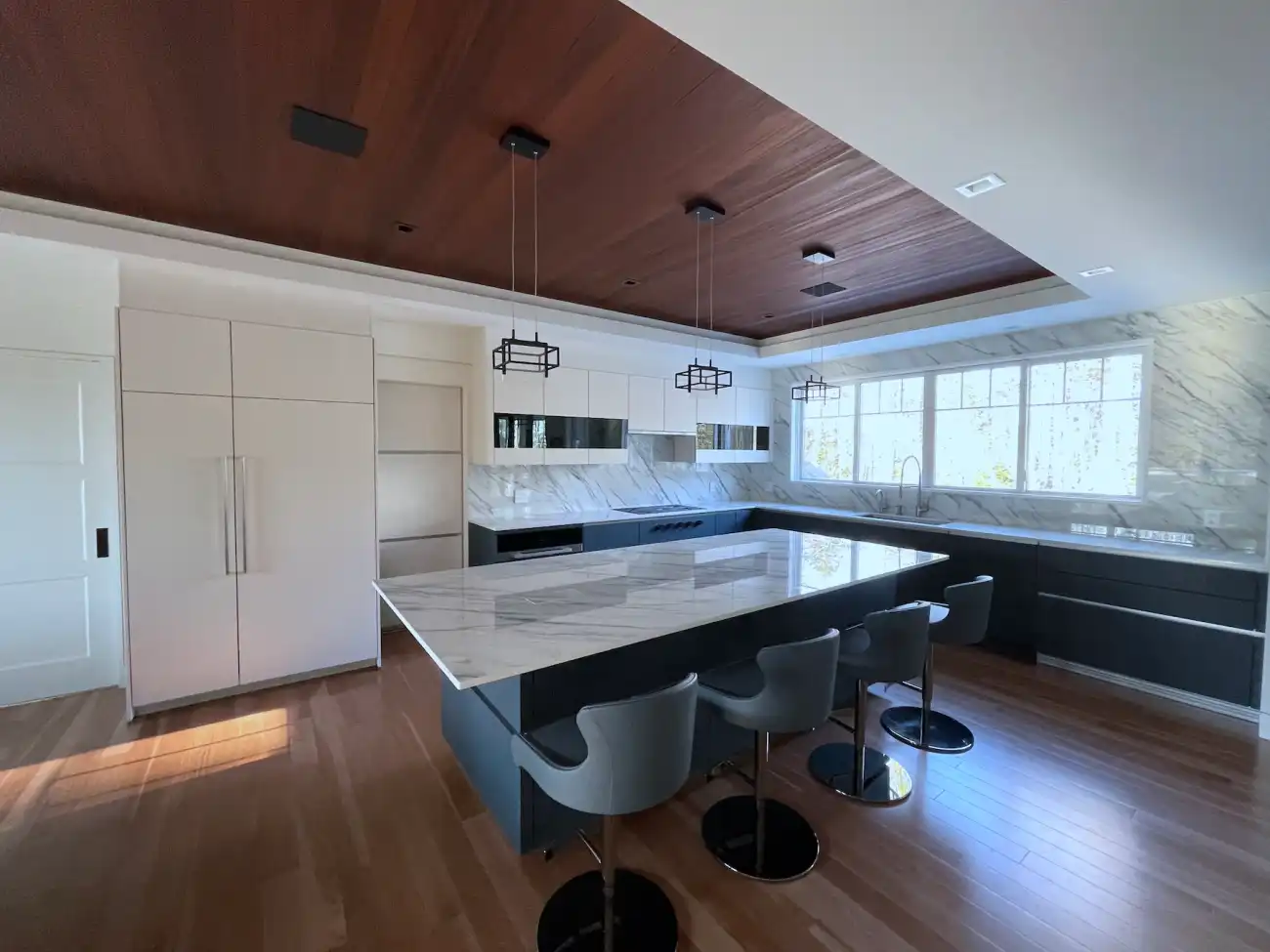 A modern kitchen with Fjord Blue cabinets and Ivory appliances designed by FORM Kitchens. There is a central island with hidden outlets and a pantry nearby in this spacious layout.